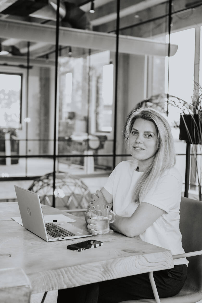 Nancy Doesburg zwart-wit zittend met laptop en kop thee – zakelijke portretfotografie